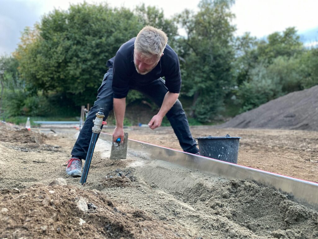 A construction worker leveling ground at a work site in Höchstenbach, Germany.